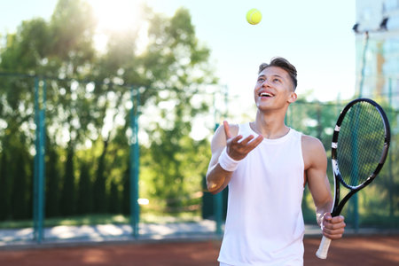 Young man playing tennis at court on sunny day. Space for textの写真素材