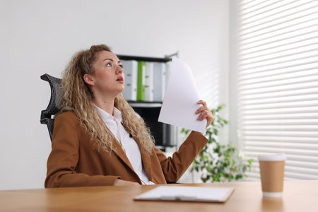 Woman suffering from heat at workplace in officeの写真素材