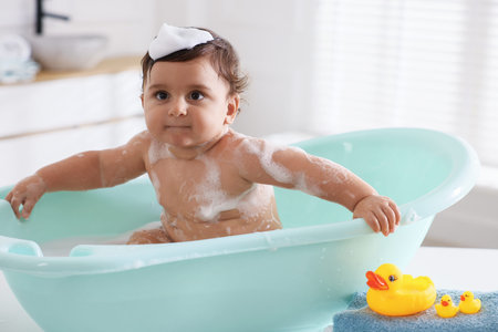 Cute little baby bathing in tub at homeの写真素材
