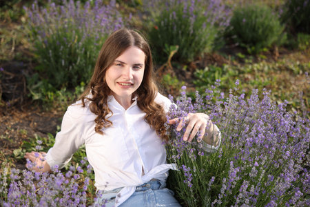 Beautiful young woman among lavender flowers in fieldの写真素材
