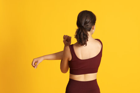 Teenage girl in sportswear stretching on orange background, back viewの写真素材