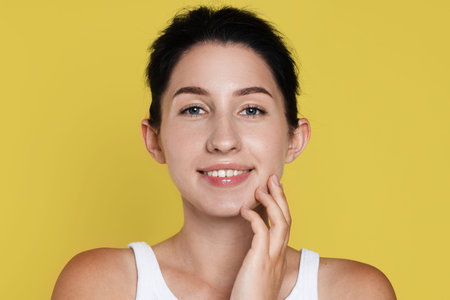 Portrait of smiling woman after dental aligners treatment on yellow background