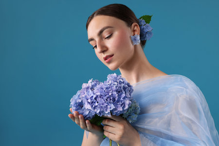 Portrait of beautiful woman with hortensia flowers and cloth on blue backgroundの写真素材