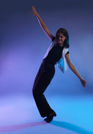 Teenage girl in tap shoes dancing on color backgroundの写真素材