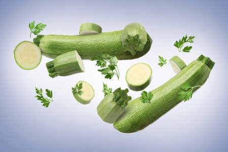 Fresh zucchinis and parsley falling on blue grey gradient backgroundの写真素材