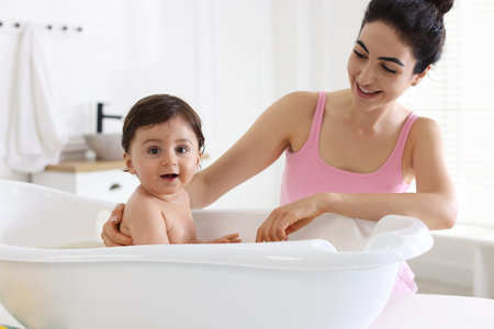 Mom giving bath to her little baby at home
