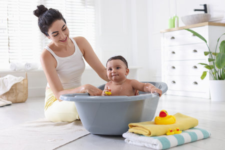Mom giving bath to her little baby at homeの写真素材