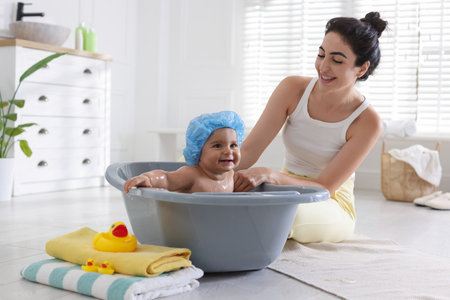 Mom giving bath to her little baby at homeの写真素材
