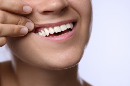 Woman showing her teeth and gums on light background, closeupの写真素材