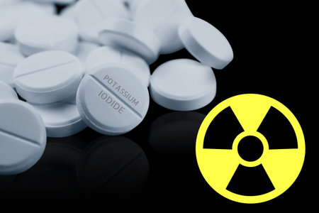 Potassium iodide pills and warning sign on black background. Iodine consumption during radioactive contaminationの写真素材