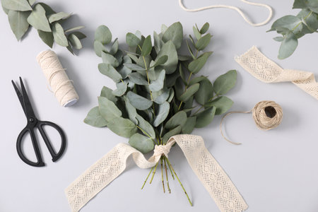 Florist. Eucalyptus branches, threads, scissors and ribbon on white table, flat layの写真素材