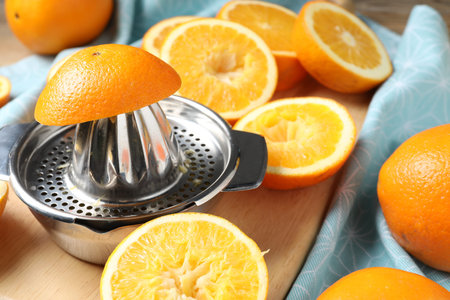 Squeezer and oranges on wooden table, closeup. Making fresh juice