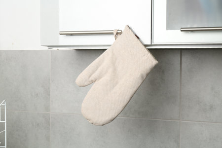 Oven glove hanging on handle of cabinet in kitchenの写真素材