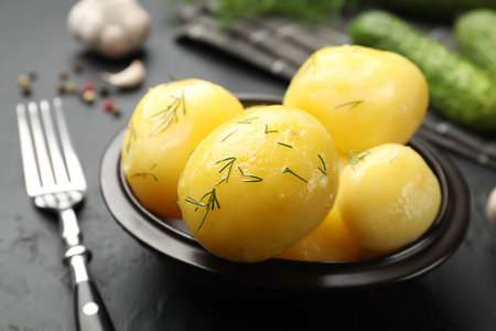 Tasty young boiled potatoes with dill on black table, closeupの写真素材