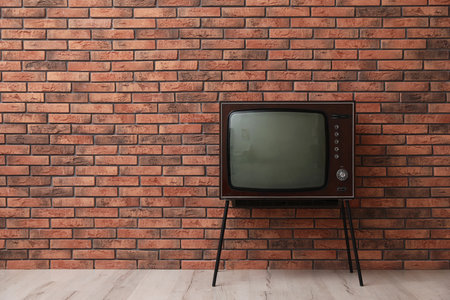 Retro TV on stand near red brick wall, space for text.の写真素材