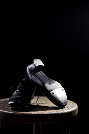 Pair of shoes for tap dance on wooden stool against black background, closeupの写真素材