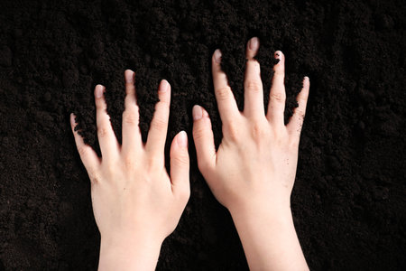 Woman touching fresh soil, top view.