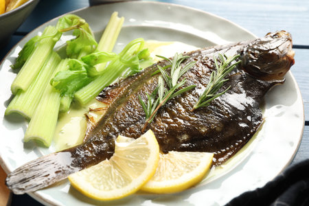 Tasty roasted flounder fish with celery served on blue wooden table, closeup. Homemade seafood dishの写真素材
