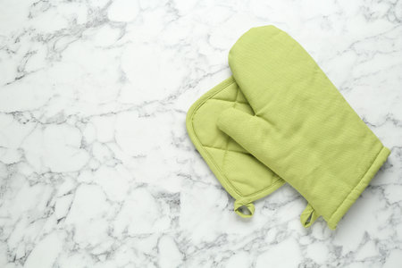 Oven glove and potholder on white marble table, flat lay. Space for textの写真素材