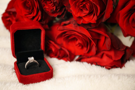 Dreams come true. Beautiful engagement ring in box and flowers on light plaid, closeupの写真素材