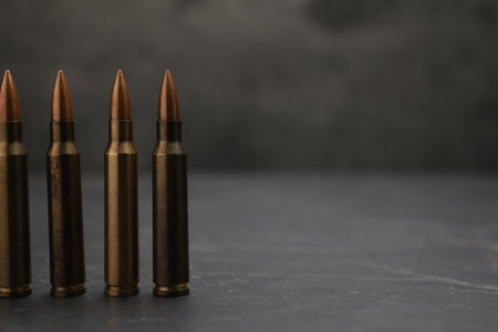 Firearm cartridges on gray table against smoke, closeup. Space for textの写真素材