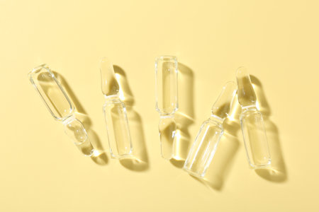Glass ampoules with liquid on yellow background, flat layの写真素材