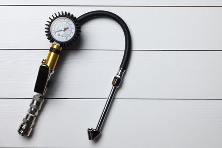 One tire inflation gun with gauge on light gray wooden table, top view