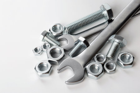 Many metal wrenches, bolts and nuts on white background