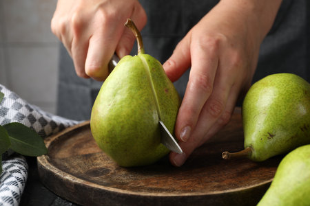 Woman cutting fresh ripe pear at table, closeupの写真素材