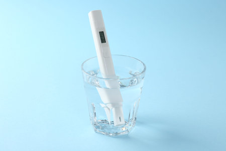 Nitrate tester in glass of water on light blue background, closeup