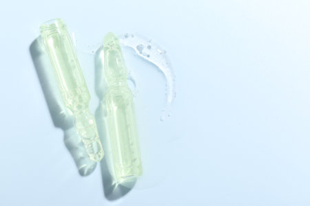 Glass ampoules with liquid on light blue background, flat layの写真素材