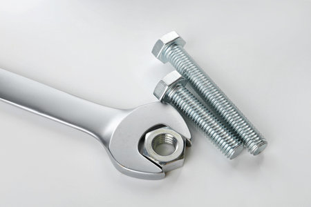 Metal wrench, bolts and nuts on white background, closeup