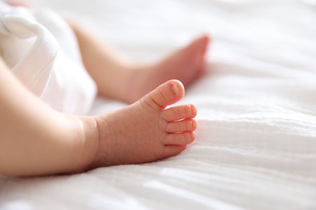 Cute newborn baby lying on bed indoors, closeup. Space for textの写真素材