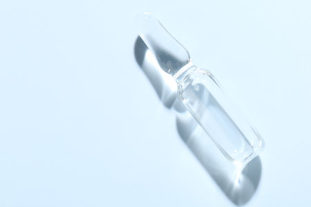 Glass ampoule with liquid on light blue background, top view. Space for textの写真素材