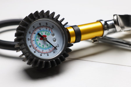 One tire inflation gun with gauge on light wooden table, closeupの写真素材