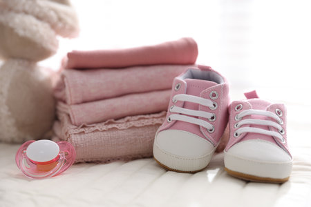Stack of clean baby clothes, shoes and accessories on bed lines, closeupの写真素材