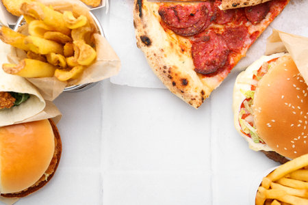 Different delicious fast food on white tiled table, flat lay. Space for textの写真素材