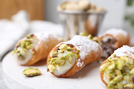Delicious cannoli with ricotta cheese, pistachios and powdered sugar on table against blurred background, closeupの写真素材