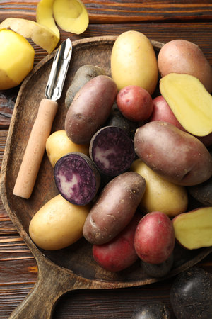 Different types of potatoes and peeler on wooden table, top viewの写真素材