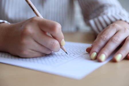 Student filling out multiple choice test at table, closeup. Passing exam