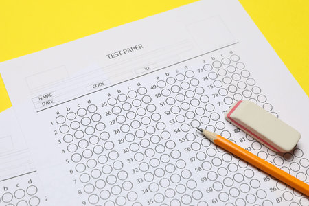 Answer sheet, pencil and eraser on yellow background, closeup. Student passing examの写真素材
