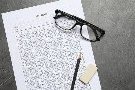 Answer sheet, glasses, pencil and eraser on gray textured table, flat lay. Student passing exam