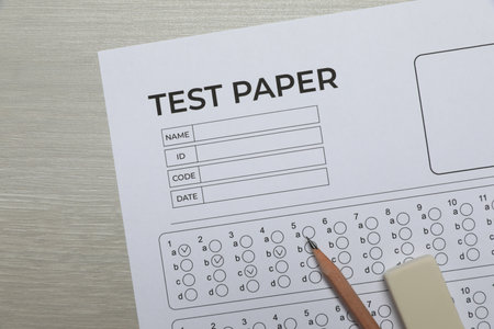 Answer sheet, eraser and pencil on wooden table, flat lay. Student passing examの写真素材