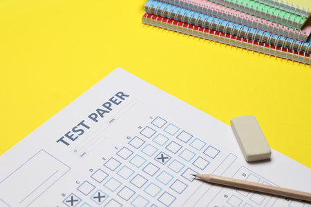 Answer sheet, pencil and eraser and notebooks on yellow background, closeup. Student passing examの写真素材