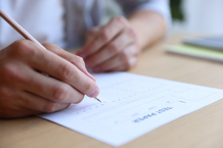 Student filling out multiple choice test at table in class, closeup. Passing examの写真素材