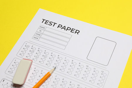 Answer sheet, pencil and eraser on yellow background, closeup. Student passing examの写真素材