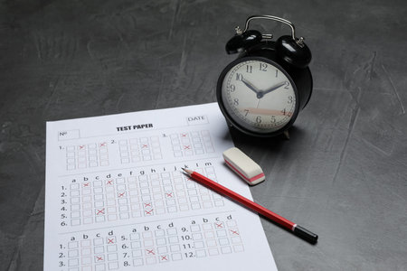Answer sheet, alarm clock, pencil and eraser on gray textured table, closeup. Student passing examの写真素材