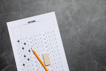 Student passing exam. Answer sheet, pencil and eraser on gray textured table, flat lay. Space for textの写真素材