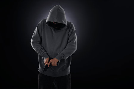 Person in mask with gun on dark background. Space for textの写真素材
