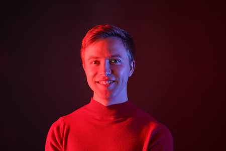 Portrait of smiling man in neon lights against dark backgroundの写真素材